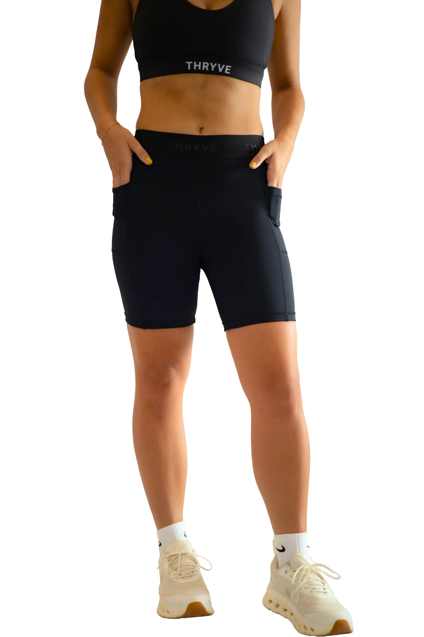 Woman wearing black high-waisted biker shorts and sports bra with pockets, activewear fashion